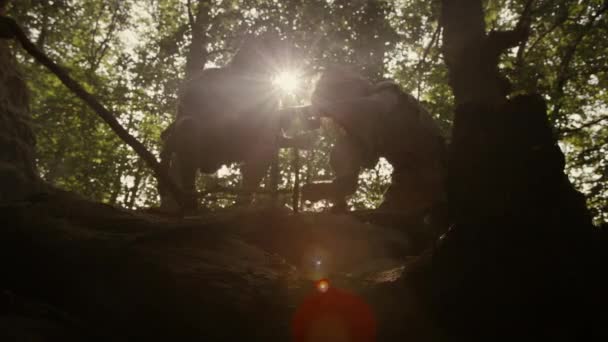 Silhouette de deux hommes des cavernes primitifs portant des peaux d'animaux essayant de faire un feu avec la méthode de forage à l'arc. Neanderthal Kindle First Man-Made fire in the Human Civilization History. Tournage à faible angle — Video