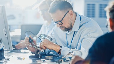 Bilgisayar Üzerinde Çalışan Elektronik Geliştirme Mühendisleri Ekibi, Anakart Tasarımı, Cihazların Bakımı ve Lehimleme Devre Kartları. Parlak ve Modern Ofis'te Çalışan Profesyoneller