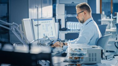 Elektronik Geliştirme Mühendisi Bilgisayar üzerinde çalışıyor, Anakart Tasarımı, Cihazların Bakımı ve Lehimleme Devre Kartları. Parlak ve Modern Ofis'te profesyonel çalışma