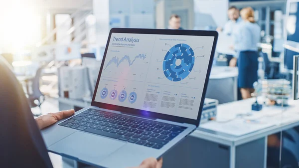 Stijlvolle vrouwelijke Industrial Robotics Engineer maakt gebruik van laptop computer met grafieken en diagrammen in de trend Analytics software. Technologie-onderzoeksfaciliteit voor machine learning en Cloud Computing — Stockfoto