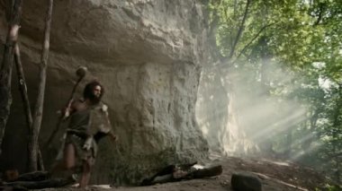 Hayvan Derisi Giyen Primeval Caveman Tutar Taş Uçlu Hammer Prehistorik Orman Etrafında Görünüyor, Hayvan Av Hunt hazır. Neandertal Ormana Avlanmaya Gidiyor. Yay Atış