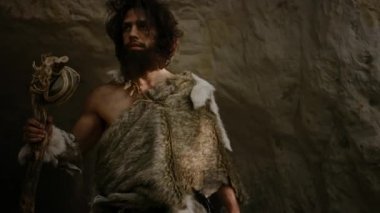 Hayvan Derisi Giyen Primeval Caveman Taş Uçlu Çekiç Tutar Mağara dan çıkar ve Prehistorik Orman Etrafında Bakar, Hayvan Prey Hunt hazır. Neandertal Ormana Avlanmaya Gidiyor. Yay Atış