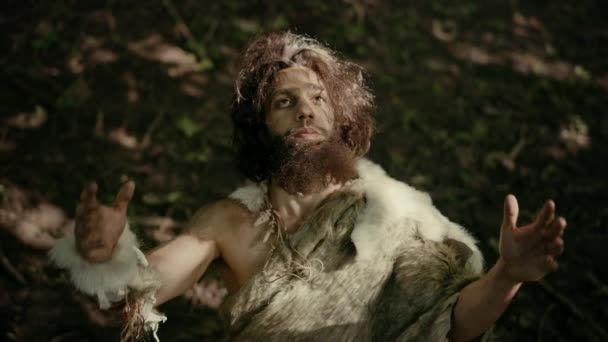 Portrait d'un homme des cavernes primitif portant de la peau animale lève les mains vers le ciel Regardant le soleil, ayant une expérience religieuse païenne. Préhistorique Néandertalien Croire et prier Dieu. Tournage à angle élevé — Video