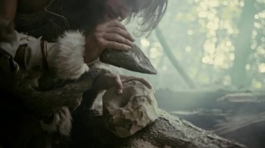 Primeval Caveman Giyen Hayvan Deri Hits Rock Sharp Stone ile, Avcılık Hayvan Prey için İlk İlkel Aracı yapar. Neandertal Flint Kayası kullanıyor. İnsan Uygarlığının Şafağı. Yavaş Hareket Closeup Shot