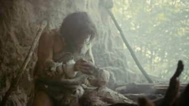 Primeval Caveman Giyen Hayvan Deri Hits Rock Sharp Stone ile ve Avcılık Hayvan Prey için Ilkel Aracı yapar. Neandertal Ilk Millstone oluşturmak için El baltası kullanarak. Yavaş Çekim Çekimi