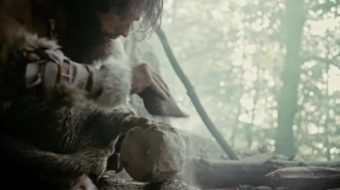 Primeval Caveman Giyen Hayvan Deri Hits Rock Sharp Stone ile ve Avcılık Hayvan Prey için Ilkel Aracı yapar. İlk Tekerlek Oluşturmak için El baltası kullanarak Neandertal. Yavaş Çekim Çekimi