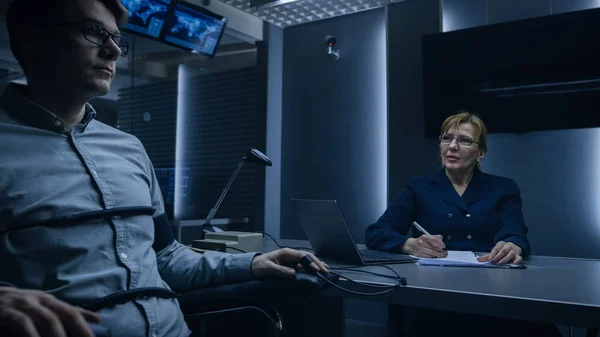 Female Special Agent Conducts Lie Detector / Polygraph Test on a Young Suspect. Expert Examiner Questions Accused in Interrogation Room. Computer Measures Physiological indices. — Stock Photo, Image