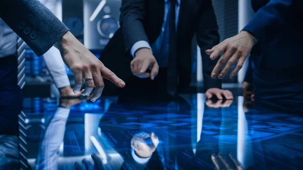 Diverse Team of Government Intelligence Agents Standing Around Digital Touch Screen Table and Satellite Tracking Suspect, Pointing at Display. Big Dark Surveillance Room. — Stock Photo, Image