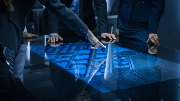 Diverse Team of Government Intelligence Agents Standing Around Digital Touch Screen Table and Satellite Tracking Suspect, Pointing at Display. Big Dark Surveillance Room. — Stock Photo, Image