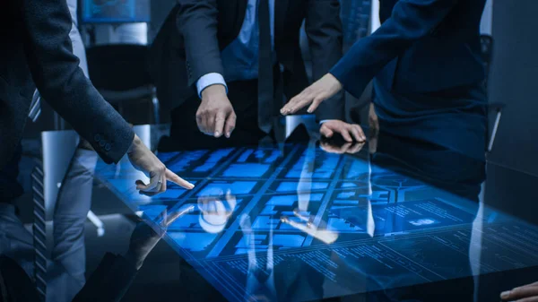 Diverse Team of Government Intelligence Agents Standing Around Digital Touch Screen Table and Satellite Tracking Suspect, Pointing at Display. Big Dark Surveillance Room. — Stock Photo, Image