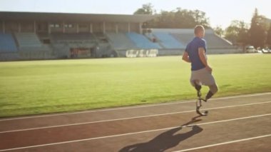Protez Koşu Bıçakları ile Atletik Engelli Fit Man Güneşli Bir Öğleden Sonra Bir Açık Stadyumda Eğitim olduğunu. Ampute Koşucu Bir Stadyum Pisti'nde Koşu. Motivasyonel Spor Görüntüleri. Takip Çekimi.