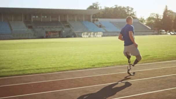 Der athletisch behinderte, fitte Mann mit den prothetischen Laufklingen trainiert an einem sonnigen Nachmittag im Freien. Der beinamputierte Läufer joggt auf einer Stadionbahn. Motivationssportaufnahmen. Kamerafahrt. — Stockvideo