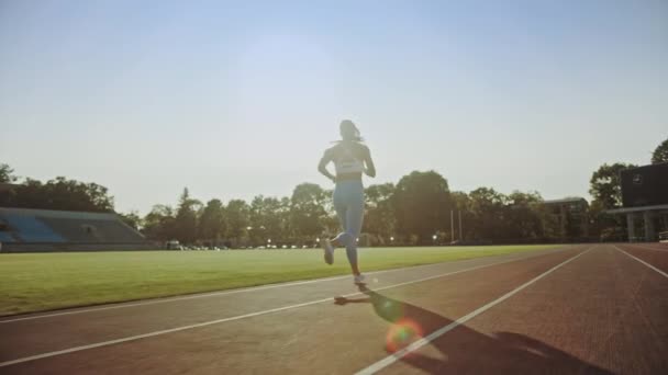 Nádherná fitness žena v světle modré atletické Top a kamaše na stadionu. Běží v teplém letním odpoledni. Sportovec dělá svou rutinní sportovní praxí na dráze. Zpomaleně.