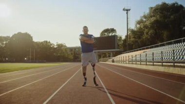 Protez Koşu Bıçakları ile Atletik Engelli Fit Man Güneşli Bir Öğleden Sonra Bir Açık Stadyumda Crossed Arms ile Poz olduğunu. Ampute Eki koşucu pistte duruyor. Motivasyonel Spor Görüntüleri.