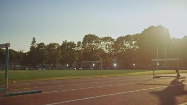 Spor Fit Man Gri Gömlek ve Şort Hurdling Stadyumda. O Sıcak Bir Yaz Öğleden Sonra Engellerin Üzerinden Atlama olduğunu. Atlet rutin spor antrenmanını yapıyor. Takip Çekimi.