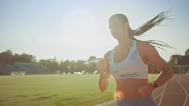 Close-up portret shot van een mooie fitness vrouw in licht blauwe atletische top joggen in een stadion. Ze loopt op een warme zomerdag. Atleet doet haar sportpraktijk op een spoor. Slow Motion. — Stockvideo
