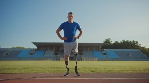 El atlético discapacitado con cuchillas protésicas está posando durante un entrenamiento en un estadio al aire libre en una tarde soleada. Amputado corredor de pie en una pista. Filmación deportiva motivacional . — Vídeos de Stock