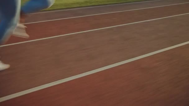 Hermosa mujer de fitness en la parte superior atlética azul claro y leggins corriendo extremadamente rápido en un estadio al aire libre. Ella está corriendo en una cálida tarde de verano. Atleta haciendo su entrenamiento. Tiro de pierna baja . — Vídeos de Stock