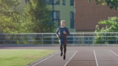 Gri Gömlek ve Şort Jogging Stadyumda Gülümseyen Athletic Fit Man. O Sıcak Bir Yaz Öğleden Sonra Hızlı Koşuyor. Atlet rutin spor antrenmanını yapıyor. Yavaş Çekim Çekimi.