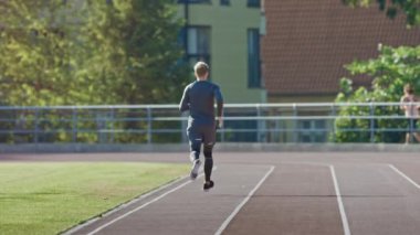 Gri Gömlek ve Şort Jogging Stadyumda Gülümseyen Athletic Fit Man. O Sıcak Bir Yaz Öğleden Sonra Hızlı Koşuyor. Atlet rutin spor antrenmanını yapıyor. Yavaş Çekim Çekimi.