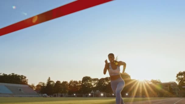 Schöne fitte Läuferin, die die Ziellinie auf einer professionellen Sportarena überquert. athletische Frau bei einem Wettkampf in einem Stadion. Siegesfeier. motivierte Brünette hebt ihre Hände nach oben. — Stockvideo