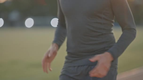 Homem de Fit Atlético em Camisa Cinza e Calções Jogging no Estádio. Ele está correndo rápido em uma tarde quente de verão. Atleta fazendo sua prática esportiva de rotina. Slow Motion Tracking Shot . — Vídeo de Stock