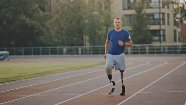 Atletische gehandicapte fit man met prothetische hardloop messen is trainen op een buiten stadion op een zonnige middag. Geamputeerde runner joggen op een stadion baan. Motiverende sport beelden. — Stockvideo