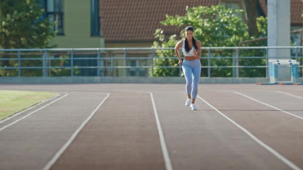 Hermosa mujer de fitness en azul claro Athletic Top y Leggings está comenzando una carrera de sprint en un estadio al aire libre. Ella está corriendo en un cálido día de verano. Atleta haciendo su práctica deportiva. — Vídeos de Stock