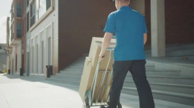 Teslimat Adam Iter El Kamyon Arabası Karton Kutular Dolu, Teslimat için Paketler. Profesyonel Kurye Verimli, Hızlı Çalışma. Şık ve modern kentsel alanda yürür. Arka Görünümü Takip Edin
