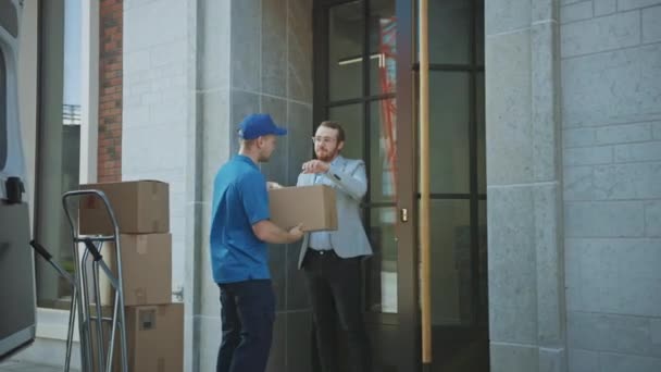 Ο άνθρωπος παράδοσης παίρνει το ταχυδρομικό πακέτο από έναν πελάτη που υπογράφει την ηλεκτρονική συσκευή POD υπογραφής. Παραδίδει φορτία στο φορτηγάκι του. Σε Business District Courier παίρνει χαρτόνι κουτί δεμάτων από έναν άνθρωπο — Αρχείο Βίντεο