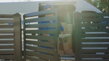 Mutlu Gülen Teslimat Adam Tutan Kart Kurulu Paketi Posta Koli Teslim Kapılardan Girer. Suburban Street Driveway arka plan teslim Van olarak