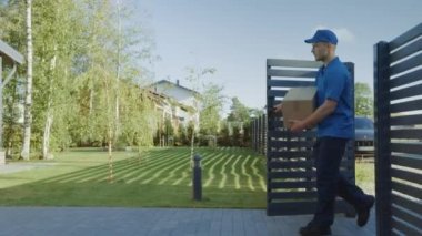 Teslimat Man Holding Kart Kurulu Paketi Kapılar dan girer ve Eve yürür ve Knocks. Posta Koli teslimi. Arka planda Güzel Banliyö Mahallesi. Aşağıdaki Yan Görünüm