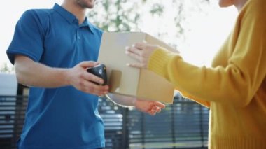 Güzel Genç Kadın Onu Karton Kutu Paketi verir Teslimat Adam Meets, O Elektronik İmza Pod Cihazı İmzalar. Banliyö Mahallesi'nde Kurye Teslim Parsel. Kutuya Odaklan