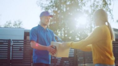 Güzel Genç Kadın Onu Karton Kutu Paketi verir Teslimat Adam Meets, O Elektronik İmza Pod Cihazı İmzalar. Banliyö Mahallesi'nde Kurye Teslim Parsel. Yan Görünüm