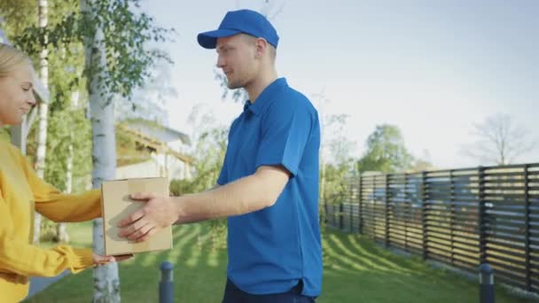 Schöne junge Frau trifft Zusteller, der ihr Pappkarton-Paket gibt, sie unterschreibt elektronische Signatur-Pod-Gerät. Kurier liefert Pakete in der Vorstadt aus. Zeitlupe — Stockvideo