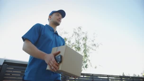 Mulher bonita jovem encontra o homem de entrega que dá seu pacote de caixa de papelão, ela assina dispositivo POD assinatura eletrônica. Courier Entregando Parcel no Bairro Suburban. Movimento lento ângulo baixo — Vídeo de Stock