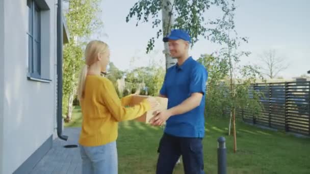 Красива молода жінка зустрічає чоловіка, який дає їй пакет картонної коробки, вона підписує електронний підпис пристрійOD. Кур'єрська доставка посилки в передмісті. Вид збоку — стокове відео