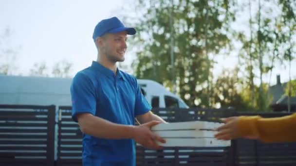 Красива молода жінка зустрічає чоловіка, який дарує їй картонні коробки, повні гарячих смачних піц. Кур'єр поставляє їжу в передмісті щасливій дівчині — стокове відео