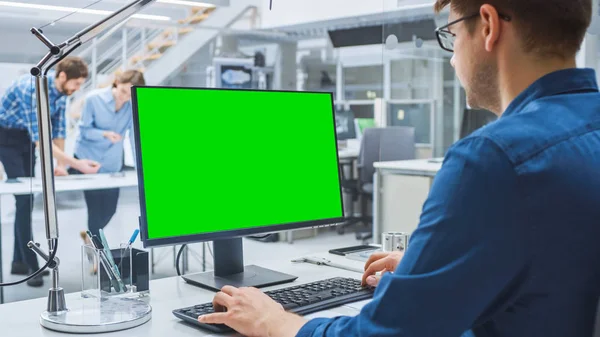 Sobre o tiro do ombro do coordenador que trabalha com o computador Mock-up verde da área de trabalho da tela. Na instalação de engenharia de fundo com especialistas que trabalham em projetos e desenhos com design industrial — Fotografia de Stock