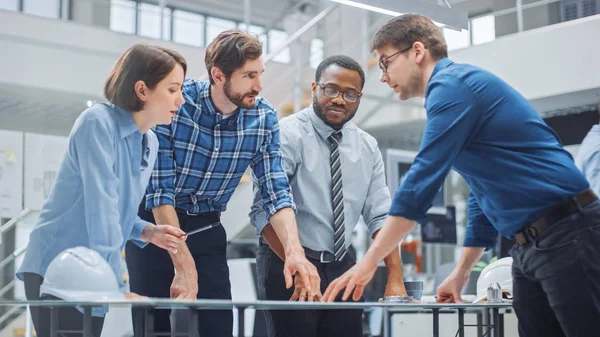 W zakładzie Inżynierii Przemysłowej: Diverse Group of Engineers, Technicians, and Specialists on a Meeting, Have Discussion, Analyse Engine Design Technical Drafts, które leżą na stole — Zdjęcie stockowe