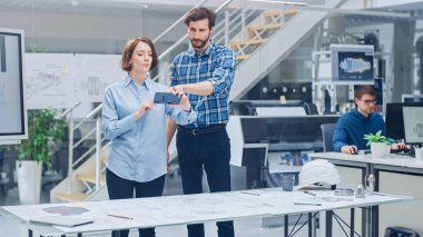 Endüstriyel Mühendislik Tesisinde: Baş Mühendis ile Kadın Tasarımcı, Motor Tasarım Teknik Tasarımlarını 3 boyutlu olarak manipüle etmek için Gelişmiş Gerçeklik Uygulaması Kullanıyor. Yüksek Teknoloji Ofisi. Model