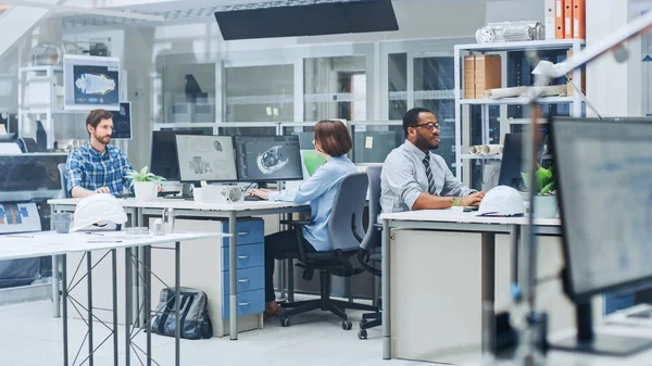 Dans l'installation d'ingénierie occupée : Divers groupes d'ingénieurs, techniciens, spécialistes travaillant sur la conception de prototypes de moteurs industriels. Les professionnels parlent, travaillent avec des dessins, utilisent des ordinateurs — Photo