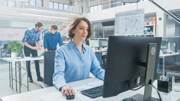 Na Instalação de Engenharia Industrial: Retrato da Engenheira Inteligente e Bela que Trabalha no Computador Desktop. No fundo Especialistas e técnicos que trabalham com rascunhos e desenhos — Fotografia de Stock