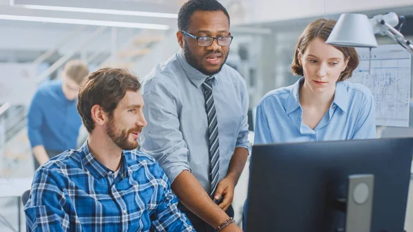 In the Industrial Engineering Facility: Portrait of the Handsome Male Engineer Working on Desktop Computer, Female Chief Engineer and Project Manager Discuss and Explain Project Details. — Stock Photo, Image