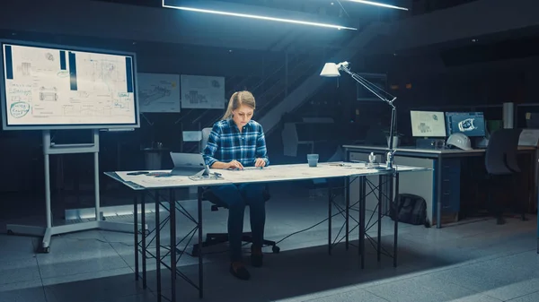 La ingeniera sentada en su escritorio funciona con planos colocados en una mesa, utiliza lápiz, regla y tableta digital. En las instalaciones de ingeniería de diseño industrial oscuro —  Fotos de Stock