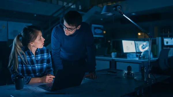 Industrial Engineering Facility: Vrouwelijke Ingenieur Werken op Desktop Computer, Project Manager Stands Naast en verklaart Bijzonderheden van de taak en Project Details. Te laat werken op Motor Prototype — Stockfoto