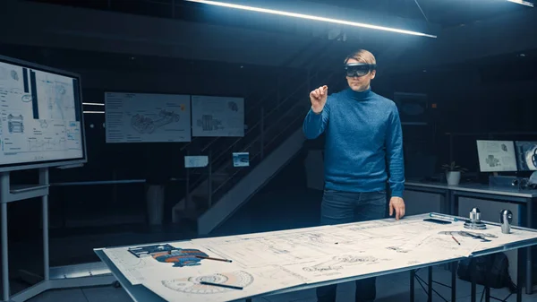 Ingénieur en développement logiciel Portant un casque de réalité virtuelle Geste et manipule des composants dans la réalité augmentée. Installation d'ingénierie a bureau avec moteur et concept de voiture plans — Photo