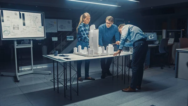 A Kreatív Építészeti Ügynökségben két profi tervező beszélget a vezető projektmérnökkel, akik egy városrész modelljén dolgoznak. Városi tervezők Funkcionális épületmodell kidolgozása. — Stock Fotó