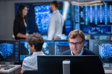 Neural ağ algoritması mimar onun iş istasyonu meşgul yaratıcı bürosunda çalışan. Birden çok ekran gösterilen AI, veri madenciliği, makine öğrenme süreçleri ile çok etnik gruptan oluşan takım çalışır.