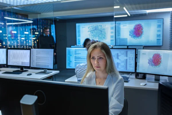 Kadın Bilgisayar Mühendisi, Uzman Ekibi ile Nöral Ağ / Yapay Zeka Projesinde çalışıyor. Ofisin 3D Görselleştirme Gösteren Çoklu Ekranı Var.